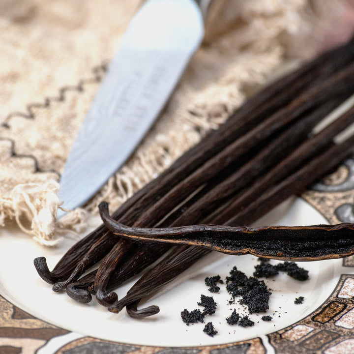 close up of sumatra vanilla beans with one split and caviar on a plate