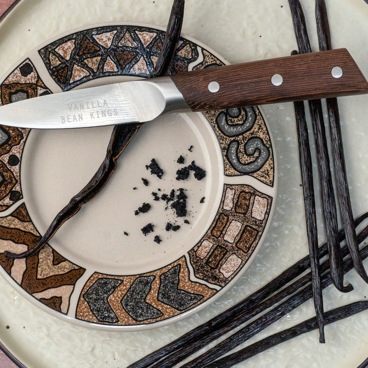 sumatra vanilla beans with one split showing caviar on a plate with a knife