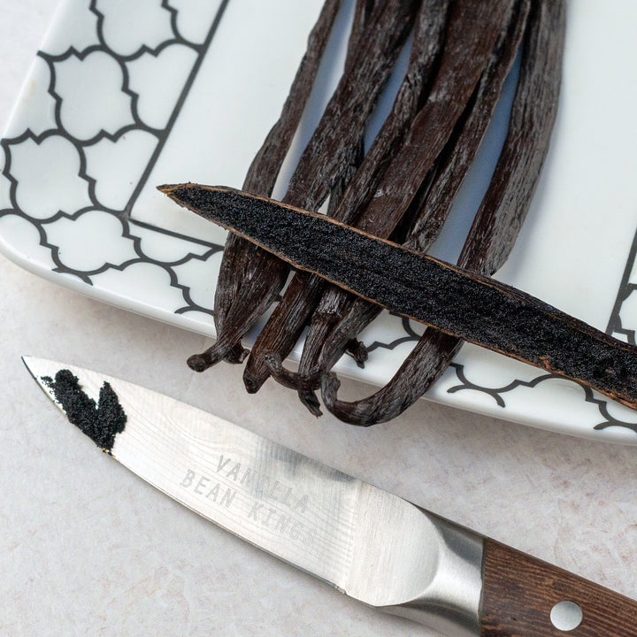 tanzania vanilla beans with one split bean on a plate with a knife showing caviar