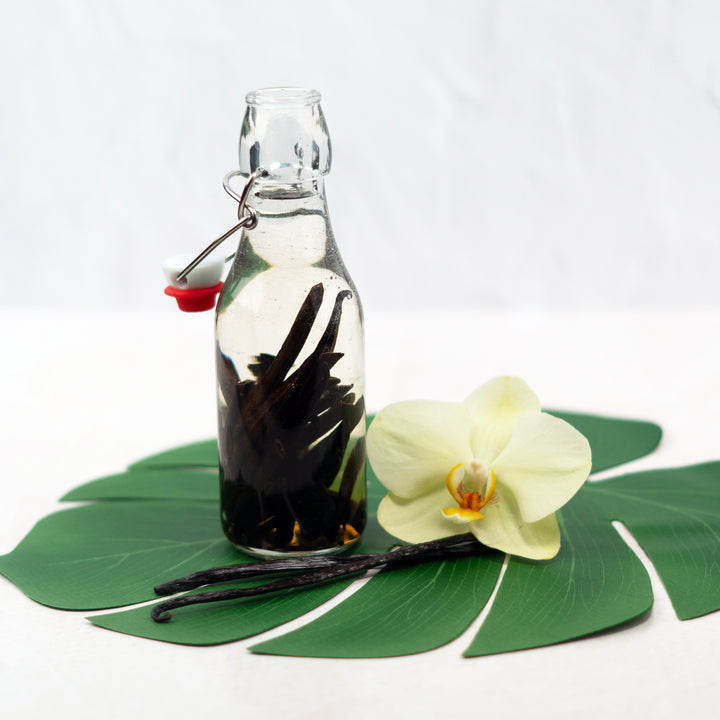 hawaiin vanilla beans extracting in glass bottle placed on leaf with flower