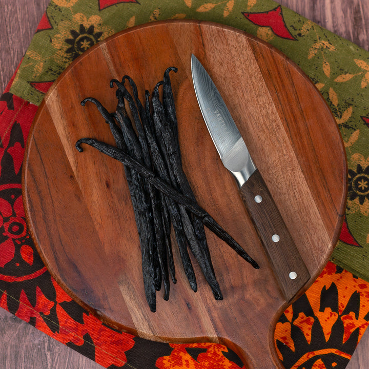 ugandan vanilla beans on round paddle cutting board with knife