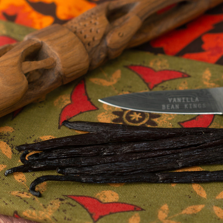 close up of ugandan vanilla beans next to wood and knife